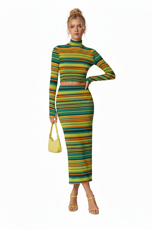 A model wearing a matching two-piece ribbed knit set featuring a long-sleeve crop top and a high-waisted midi skirt, both decorated with vibrant horizontal stripes in green, yellow, orange, and blue. She is holding a small light blue handbag and wearing clear high-heeled sandals, set against a plain white background.